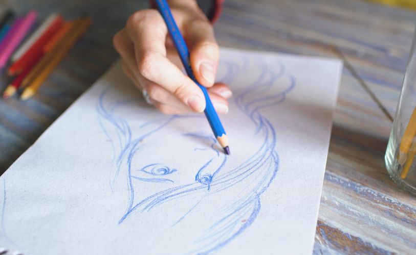 hand sketching a picture of a girl using a blue color penciled