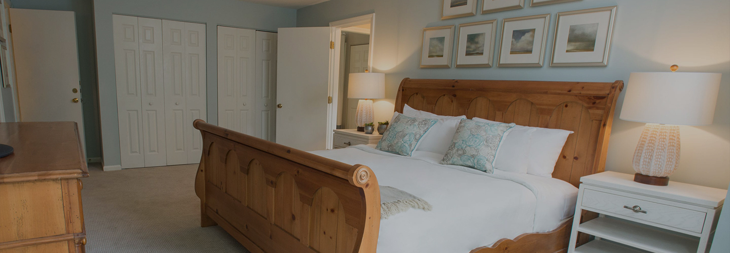 a clean guestroom with a wood bed and white linens