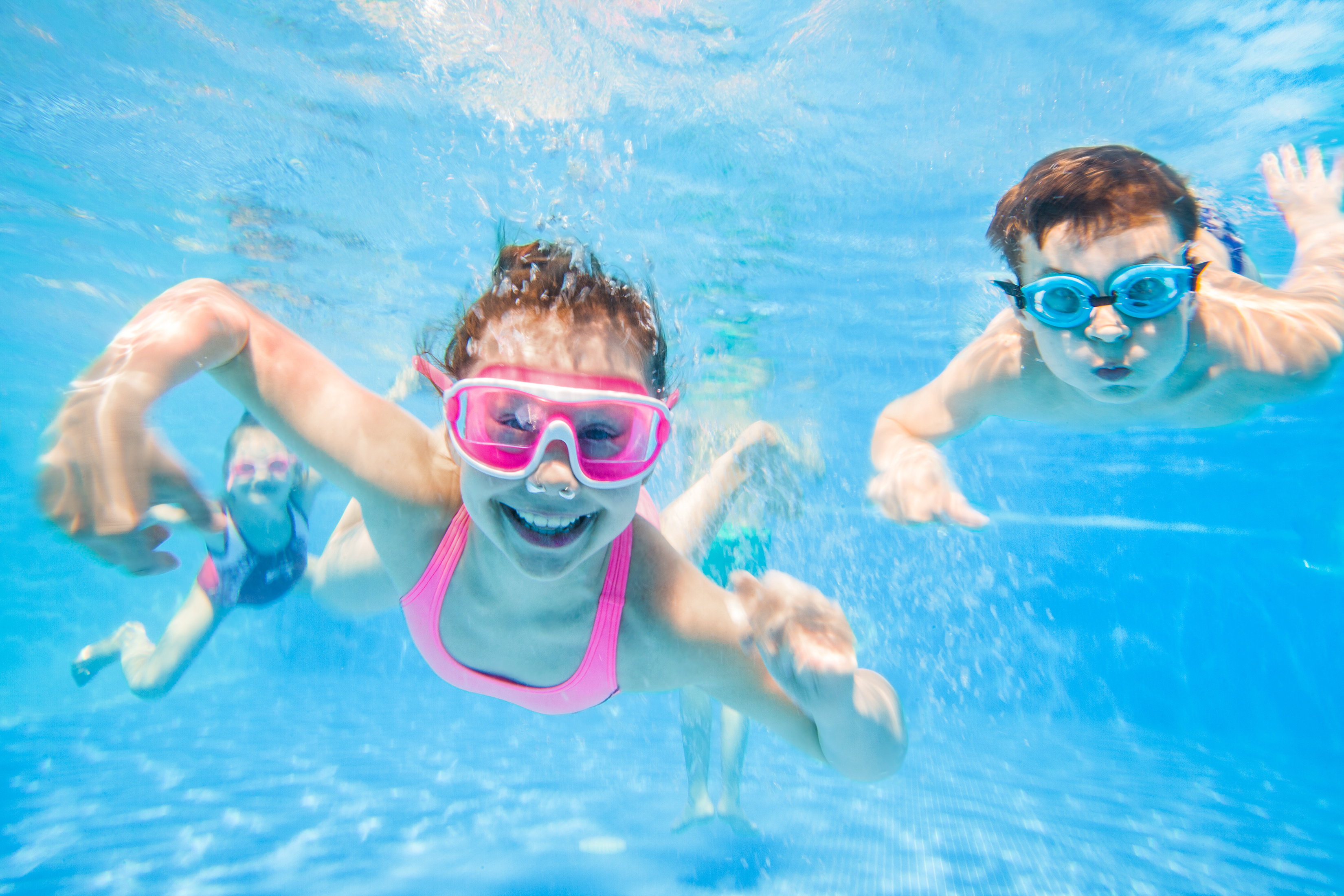 three children swimming underwater in a pool