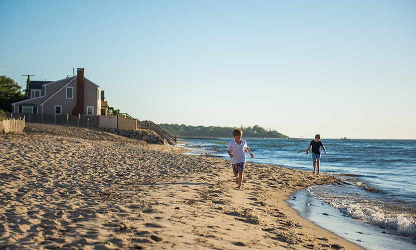 two young boys running on the beach near the water