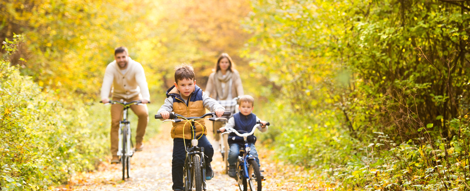 family of 4 riding bikes in a fall forest