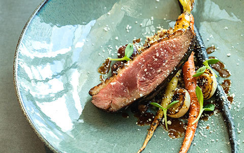 Plated dish featuring duck and roasted carrots