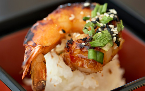 Grilled shrimp on top of rice with green onion garnish