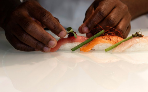 Close up of chef's hands plating raw sushi 