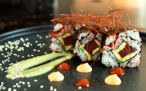 Sushi roll with sauce and herb garnish