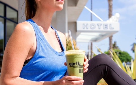 img-woman sitting outside holding a green smoothie