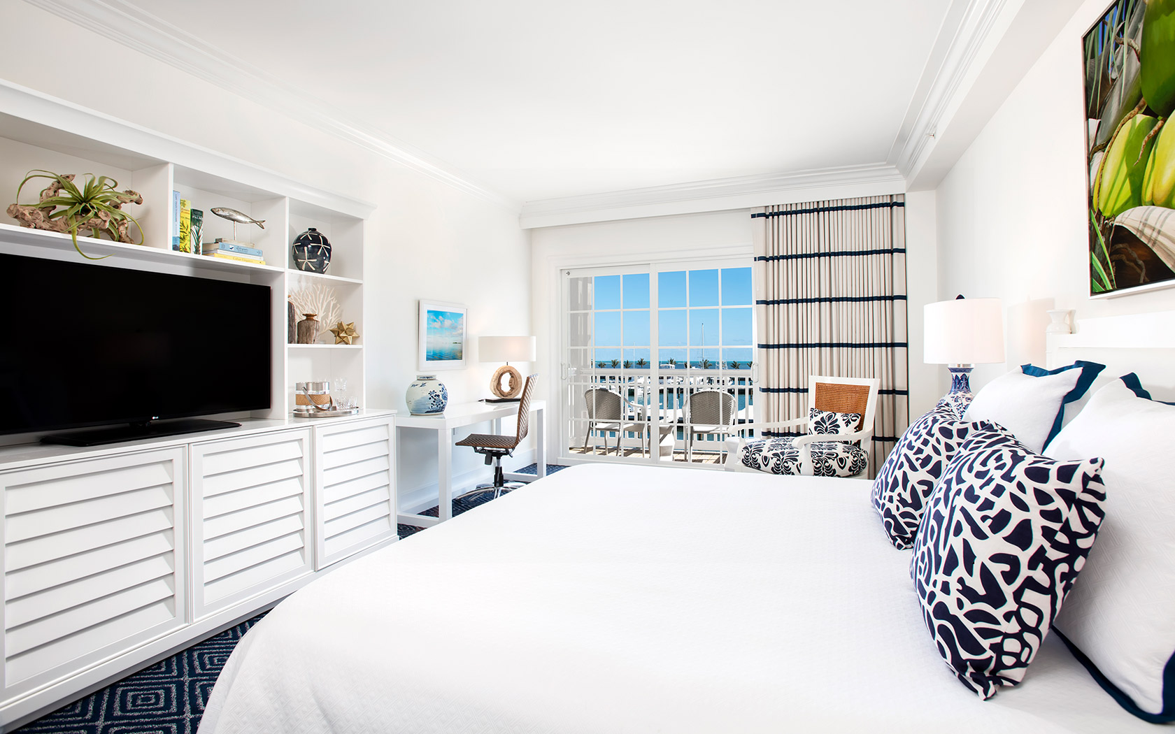 Internal view of a big room with a white and blue bed and a balcony 