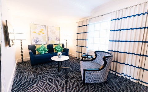 hotel room seating area with a blue couch and blue patterned chair