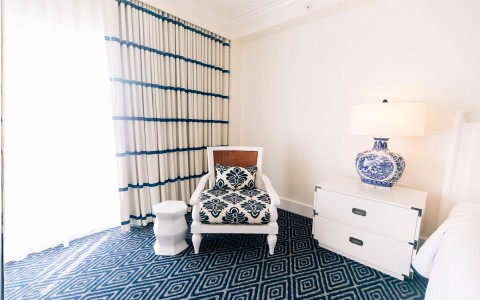 corner room chair with white night stand and blue and white lamp 