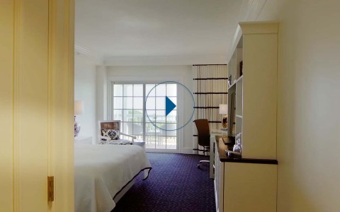 ocean view balcony with a king sized bed with a white comforter and blue carpet