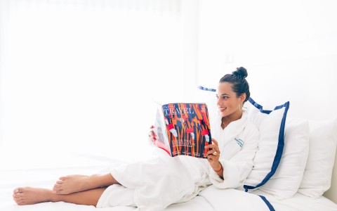 lady relaxing on queen bed reading a travel magazine