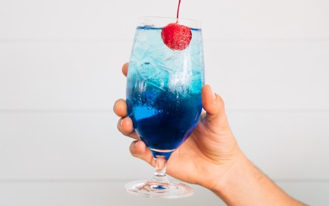 blue alcoholic beverage topped off with a cherry 