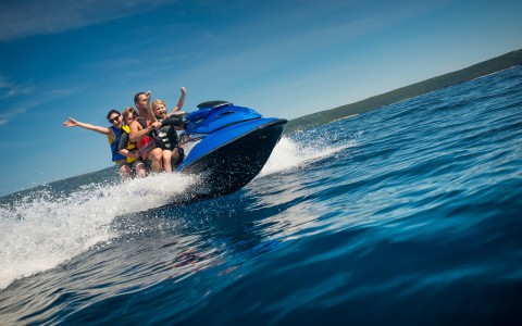 family enjoying some fun on the water riding a blue jet ski 