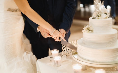 couple cutting into a white three layered cake