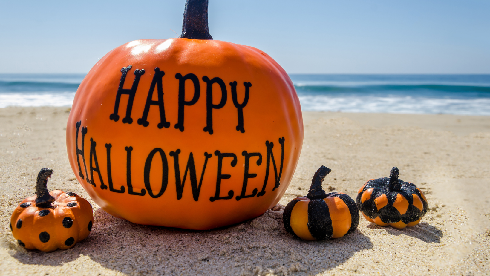 Happy Halloween on a painted pumpkin on the beach