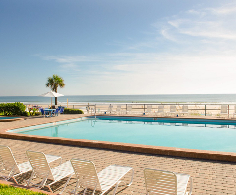 White loungers next to pool overlooking the beach