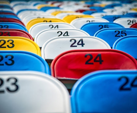 Close up of colorful chairs with numbers lined up on bleachers