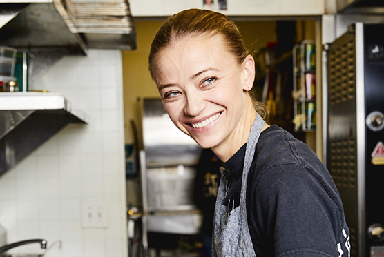 Woman chef smiling and looking to the right side in the kitchen