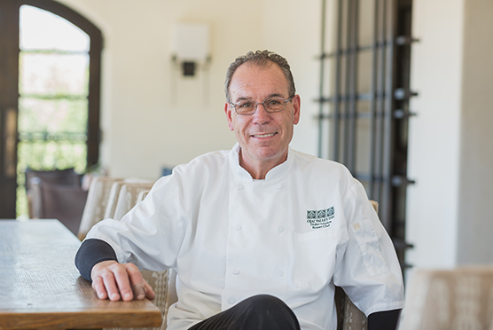 Ojai chef wearing glasses sitting and smiling straight to the camera 