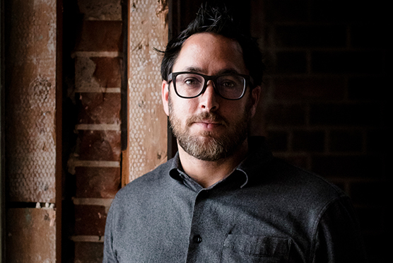Guy wearing black glasses and black shirt looking straight to the camera
