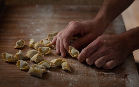 hands of a chef making some small raviolis 