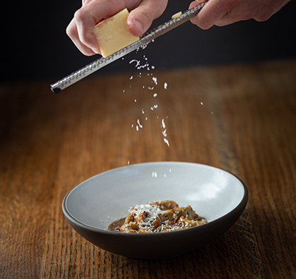 chef finishing a italian dish with some cheese on the top