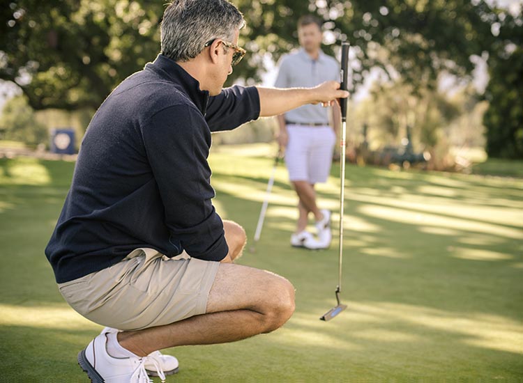 kneeling man looking at his golf club