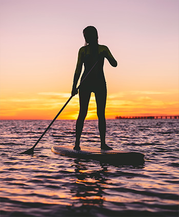 person standing on a paddleboard during sunset