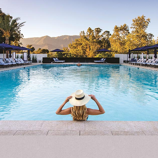 Woman standing at the edge of a pool with a hat on