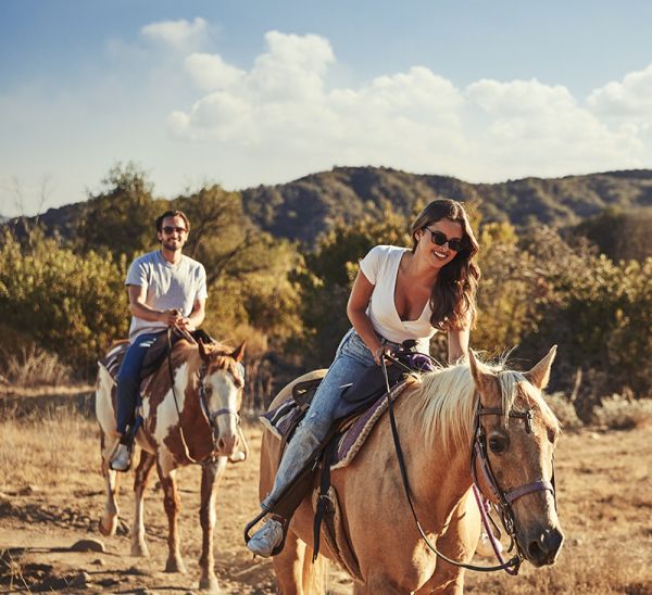 Two people horseback riding together in the woods