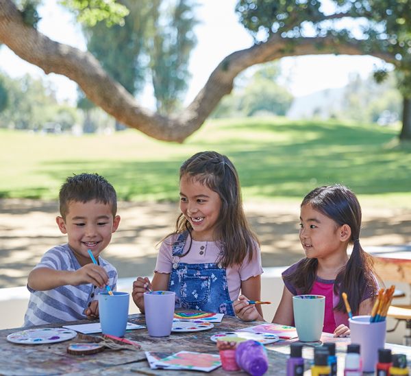 A couple of children doing arts and crafts in the park