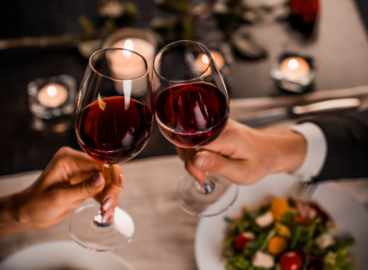 couple cheersing glasses of red wine at romantic dinner