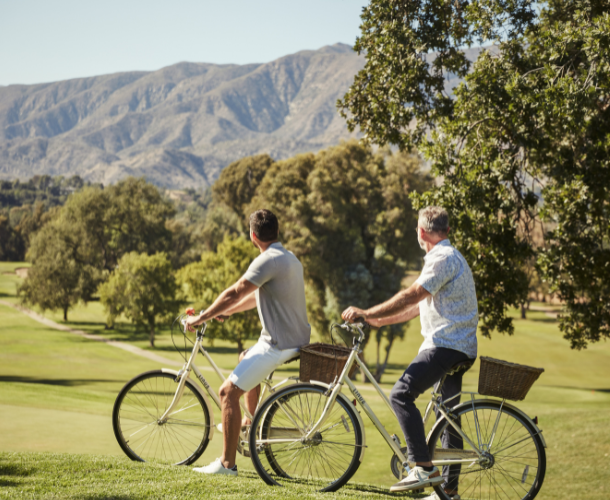 Two men riding bicycles while looking at the mountains
