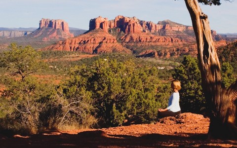 woman doing yoga with the red rock mountains in the distance
