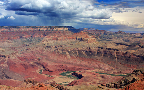 the grand canyon with river running through it and blue skies with clouds