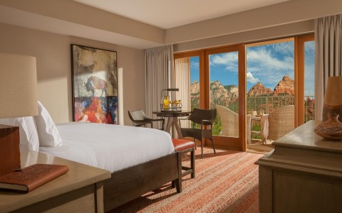 guest room with a bed facing glass doors with a view of the red rock mountains