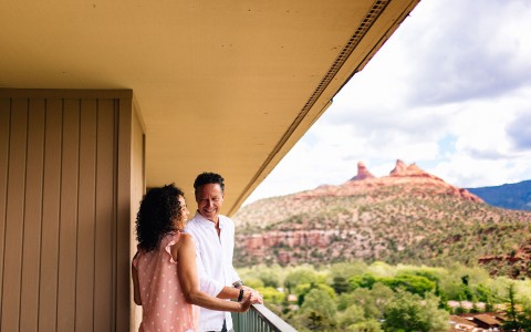 a couple smiling next to each other on the balcony of their guest room