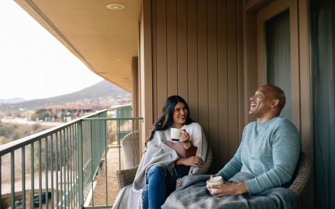 a couple relaxing on the balcony of their guest room and smiling together