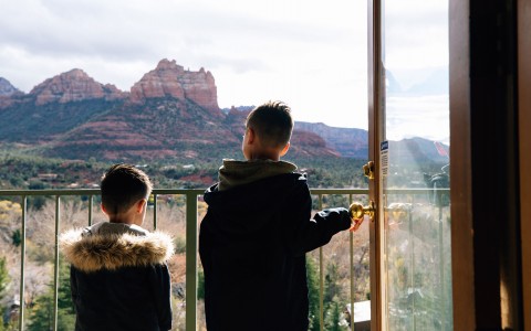 two young boy siblings staring at the grand views of the arizona landscape wearing big jackets