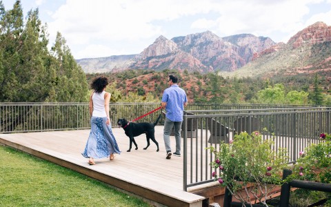 a couple walking their dog on the orchards inn property with grand views of the surrounding green trees and rock mountains