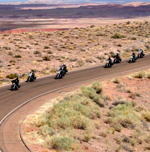group of people riding motorcycles on a deset road