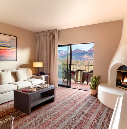 guest suite area with a tan couch, fireplace, coffee table, chair, and balcony area