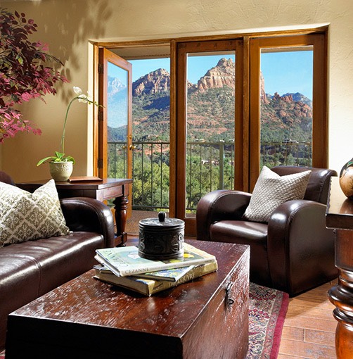 guest living room area with leather couches and chairs, dark wood coffee table, and balcony