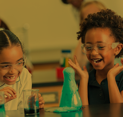 Two young girls laughing as they conduct a science experiment