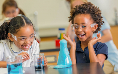 Two young girls laughing as they conduct a science experiment