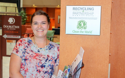 Woman smiling next to a recycling poster