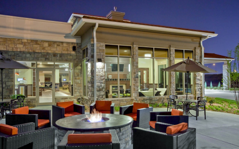 Hotel exterior patio area with fire pit surrounded by eight cushioned chairs