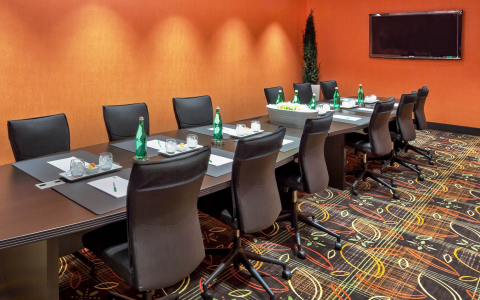 Conference room with a long table surrounded by 12 chairs and a flat screen TV mounted on the wall