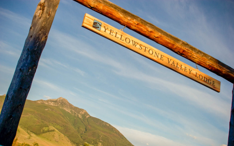 Yellowstone Valley Lodge sign on wooden posts with a mountain in the background