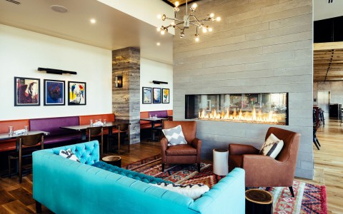 hotel lobby with multicolored couches in front of a glass fireplace